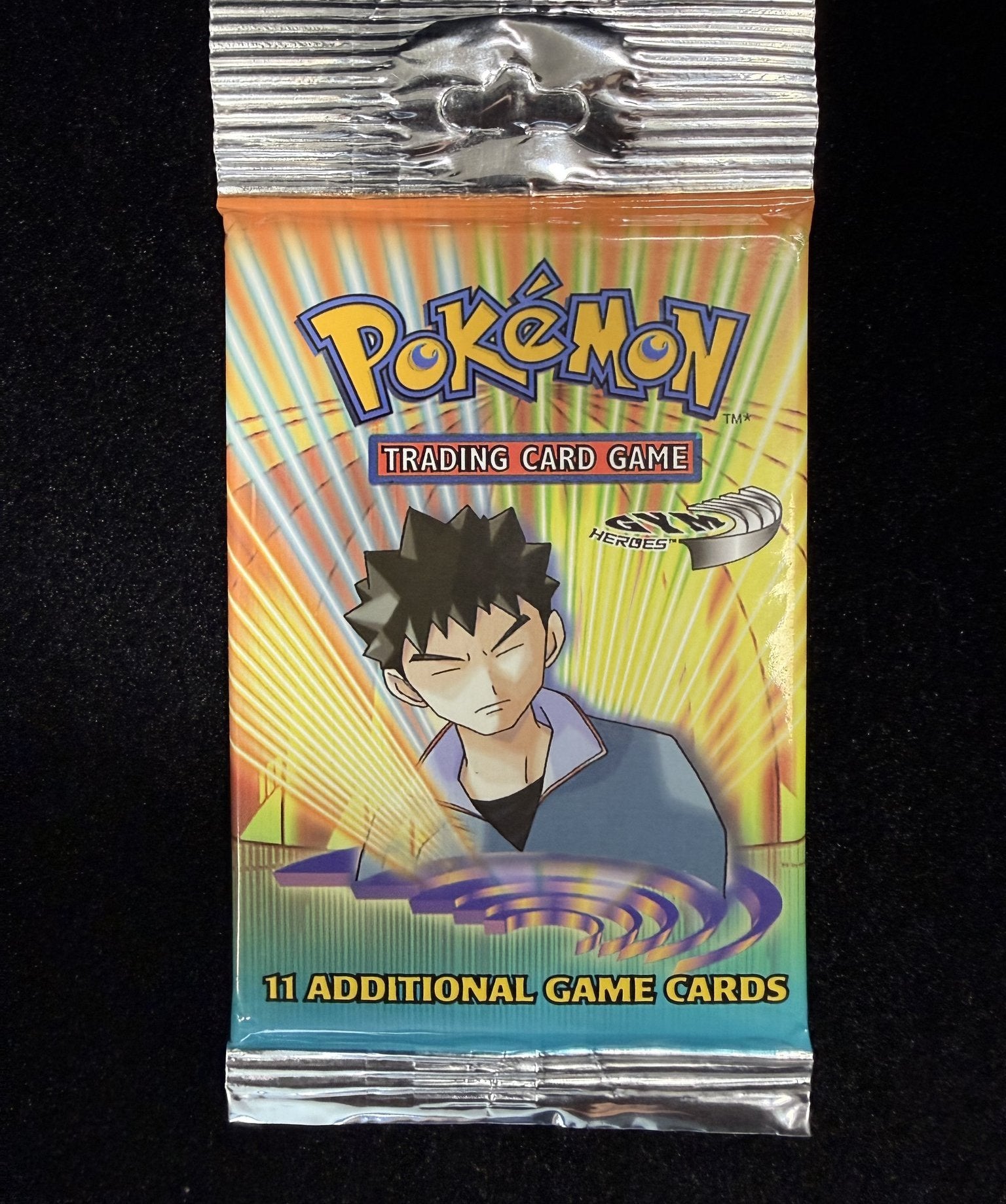Front of a sealed 2000 Pokemon Gym Heroes booster pack with Brock artwork, reading Trading Card Game and 11 Additional Game Cards
