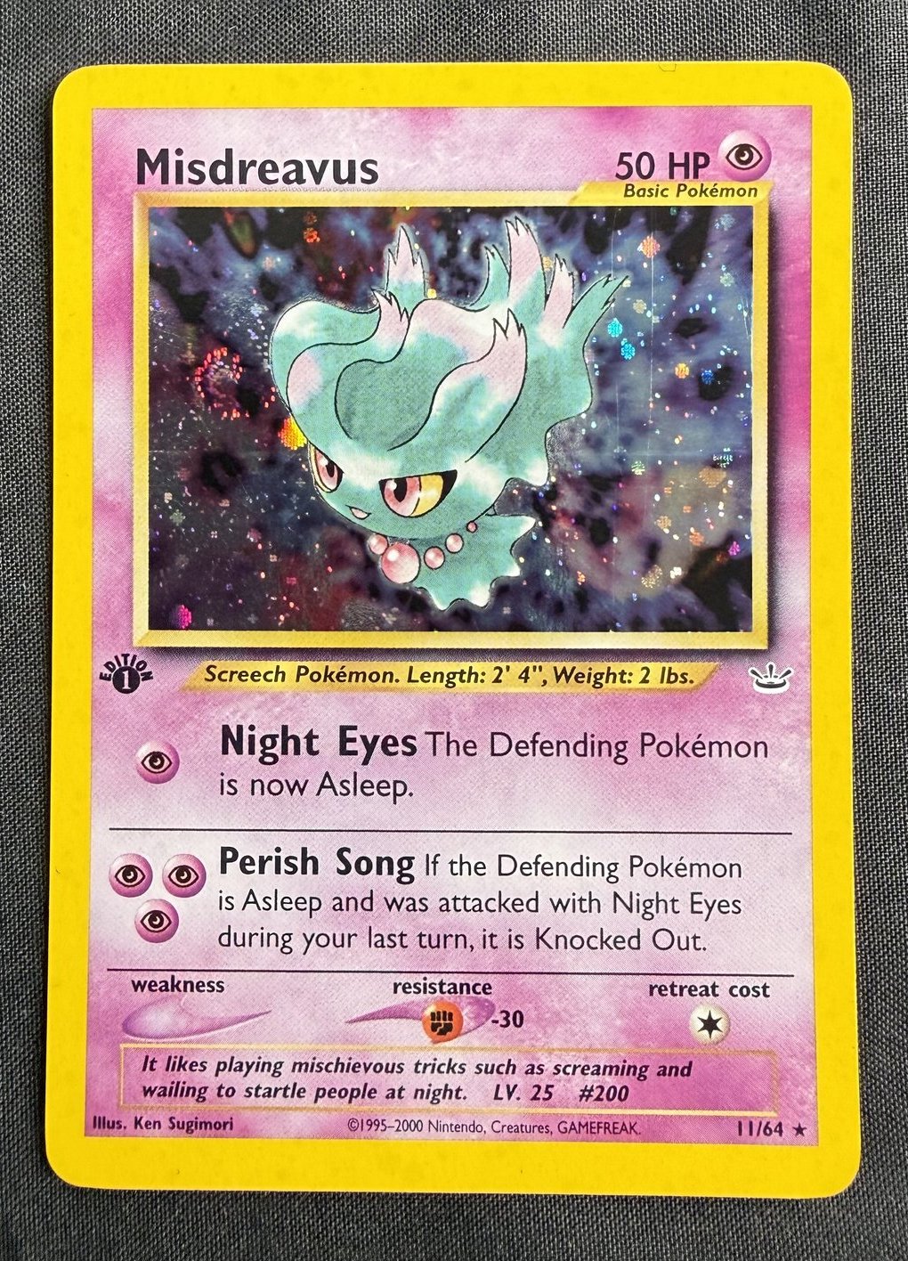 Front of a 2001 Pokemon Neo Revelation Misdreavus 1st Edition holo card, number 11/64, showing the Screech Pokemon against a cosmos holofoil background